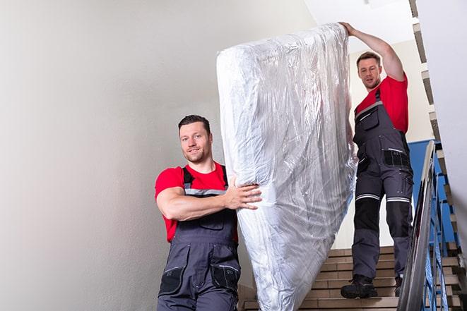 two workers carrying a heavy box spring out of a bedroom in Blossom